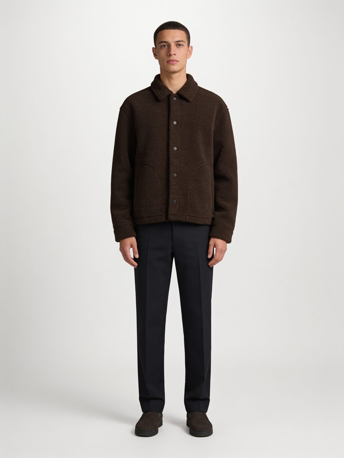 Model in a brown button-front overshirt on a light grey studio background